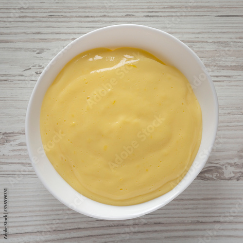 Homemade vanilla custard pudding in a white bowl, overhead view. Flat lay, top view, from above.
