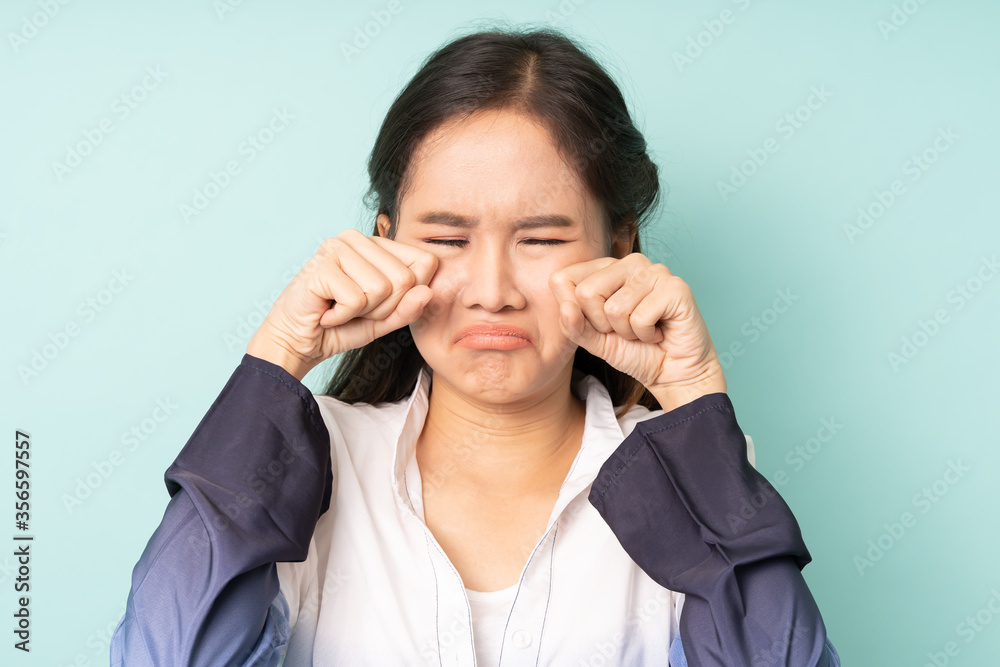 Portrait of young asian woman crying on blue background. Cute people. Portrait of young asian woman crying on blue background. Cute people.