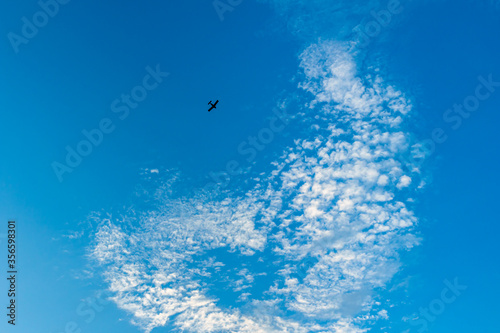 a heart-shaped cloud in the blue sky and a plane © Anatolii