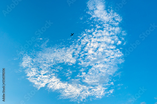 a heart-shaped cloud in the blue sky and a plane