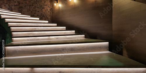 Illuminated staircase with wooden steps and illuminated at night in the interior of a large house