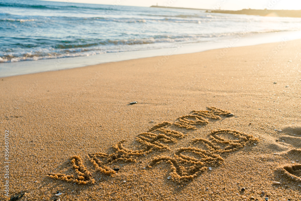 Obraz premium 2020 Vacation handwritten on sandy beach natural outdoors background.