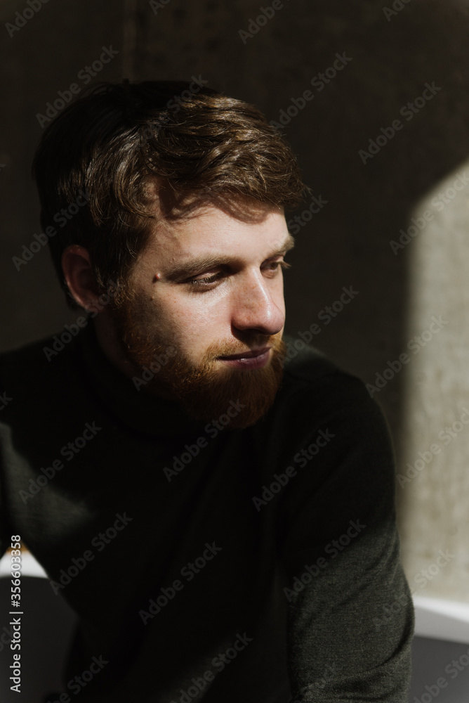 A young bearded man sits thoughtfully on the sofa. A young bearded man sits thoughtfully on the sofa.