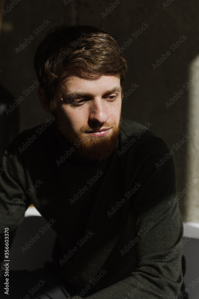 A young bearded man sits thoughtfully on the sofa. A young bearded man sits thoughtfully on the sofa.
