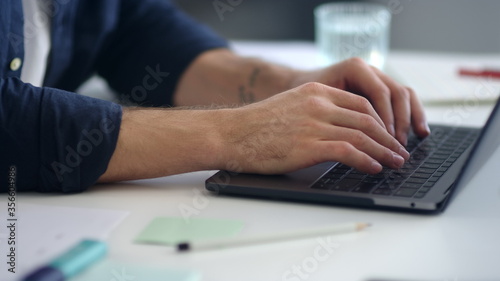 Close up man hands working laptop computer. Male professional typing computer