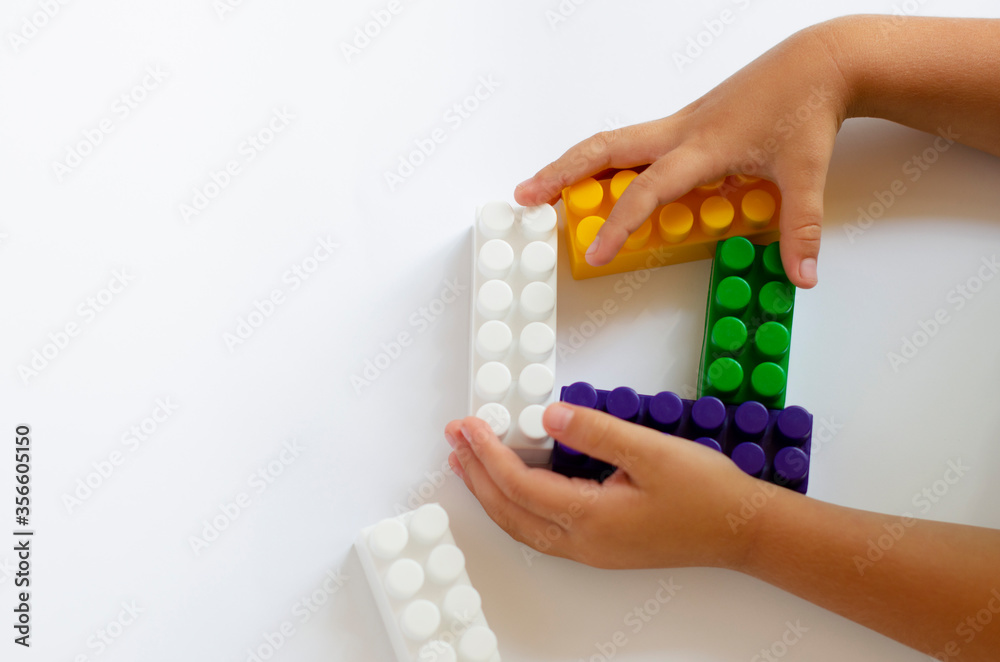 Obraz premium children`s plastic constructor on a white background with children`s hands