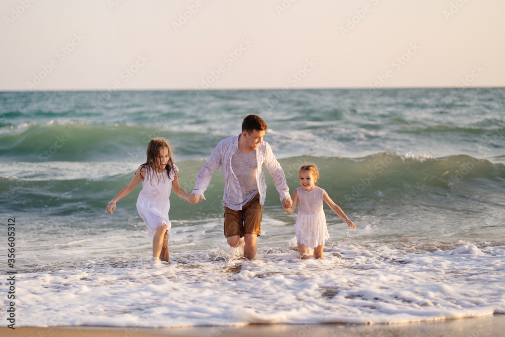 wet dad and daughters swimming in sea in clothes, playing and having fun.
