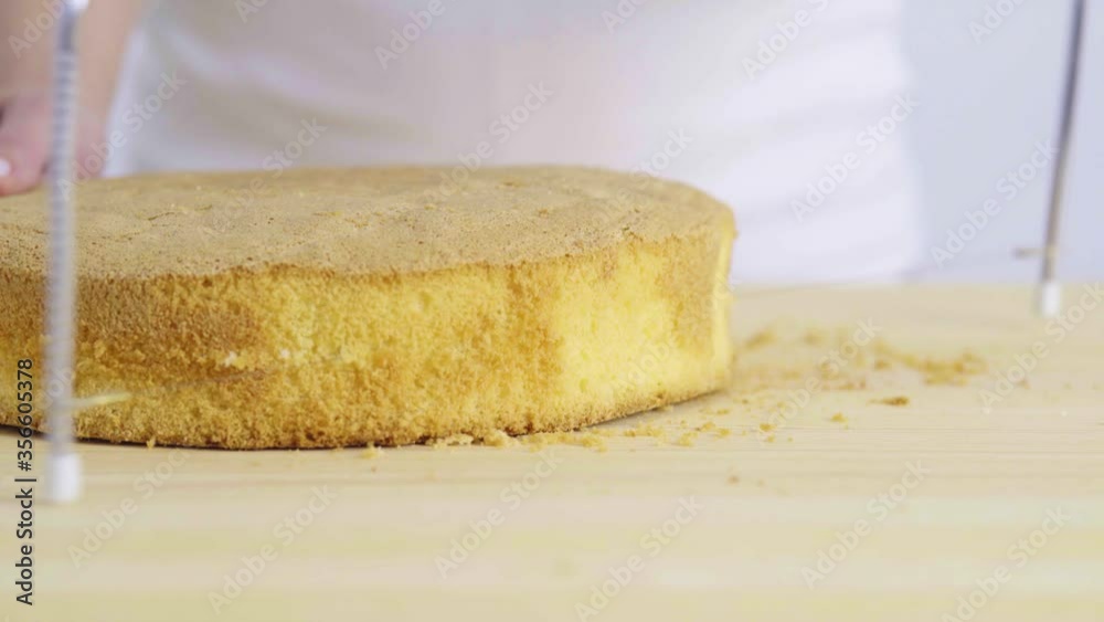 close-up girl in the kitchen cuts a sponge cake with a string. close-up girl in the kitchen cuts a sponge cake with a string.