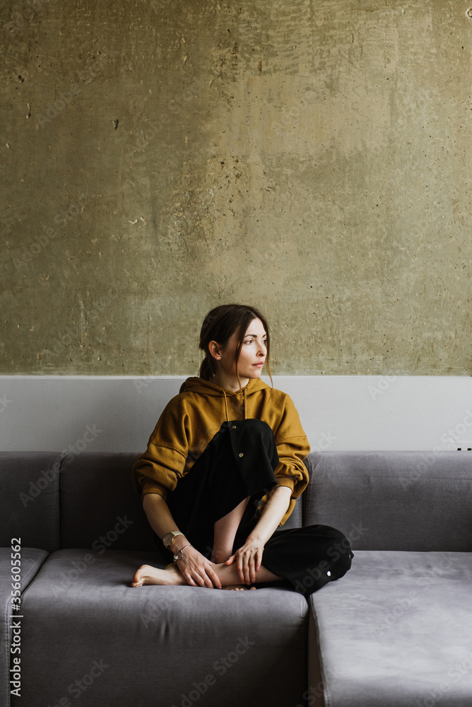 A beautiful young woman is sitting on a sofa at home. A beautiful young woman is sitting on a sofa at home.