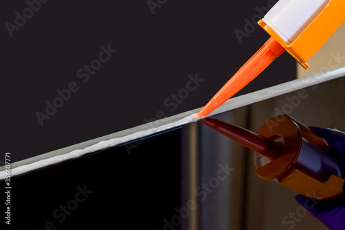 Glue gun or caulk gun with silicone isolated on dark background. photo