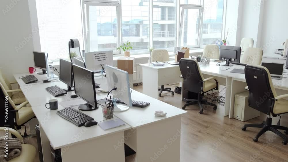 Dolly-out shot of desks and computers in empty office amidst covid-19 pandemic