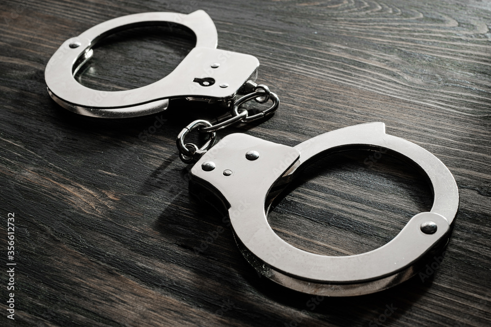 metal handcuffs on a wooden table metal handcuffs on a wooden table