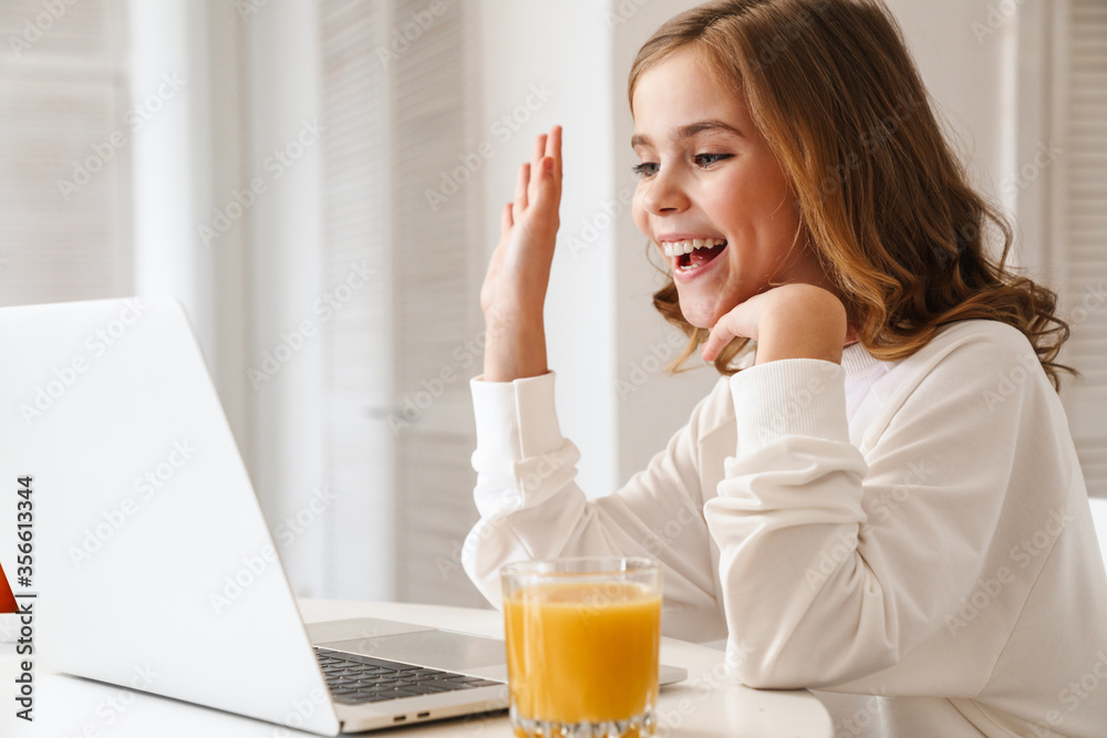 Photo of cheerful girl taking video call on laptop and waving hand Photo of cheerful girl taking video call on laptop and waving hand