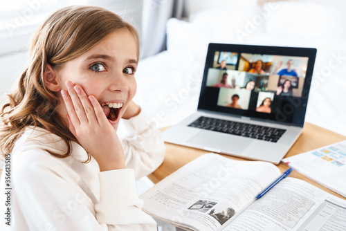 Photo of excited girl expressing surprise while studying online