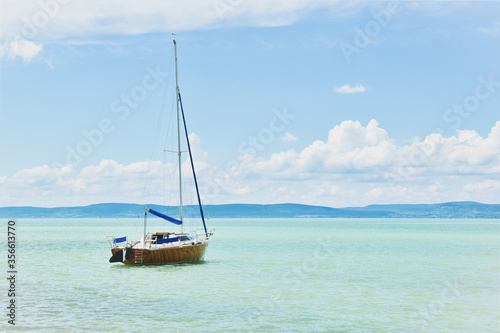 Sailboat floating peacefully on the azurre blue water of Lake Balaton  clear blue water with a sailing boat daylight view summer water sport  Lake Balaton  Hungary landscape  vacation on the beach