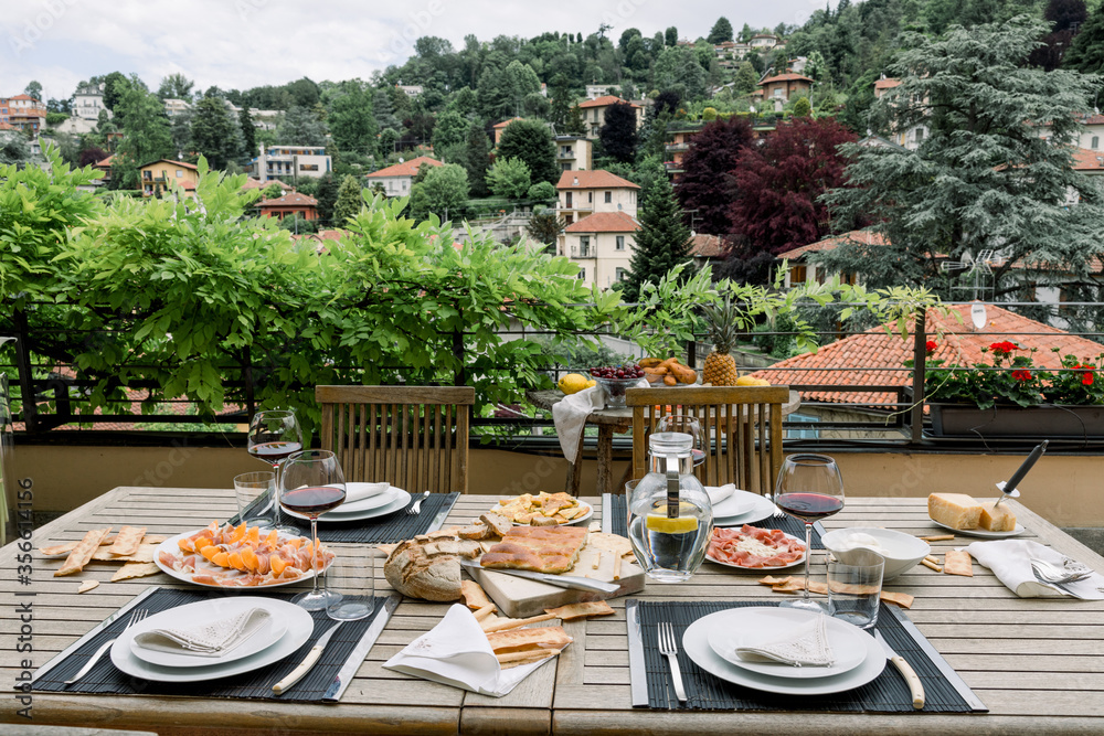 dining table with wooden chairs set on the terrace with beautiful italian landscape. food concept