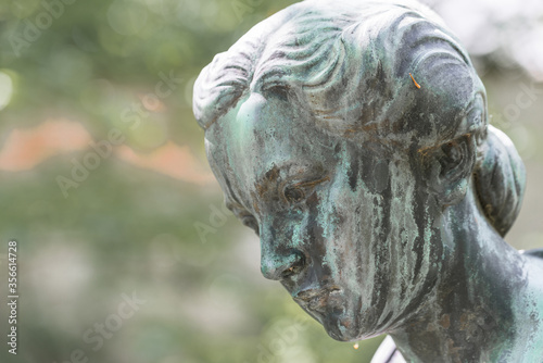 Nahaufnahme einer weiblichen Bronzestatue Frau mit kurzen Haaren mit Kreuz und Strickjacke in einem Park, Deutschland photo