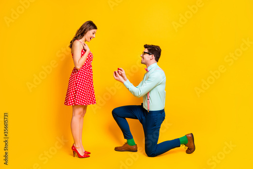 Full body profile photo of pretty lady handsome guy couple proposing girlfriend stand one knee hold diamond ring box wear red dress shirt bowtie isolated yellow bright color background photo