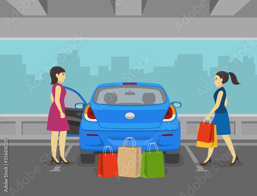 Two female friends coming from shopping and going to load the car trunk with purchase. Back view of mini car. Parking lot.