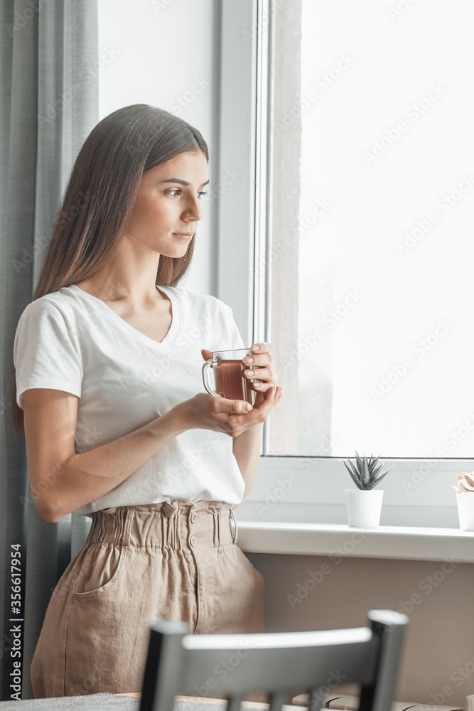 Beautiful woman drinking morning tea behind window Beautiful woman drinking morning tea behind window