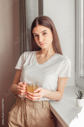 Beautiful woman drinking morning tea behind window