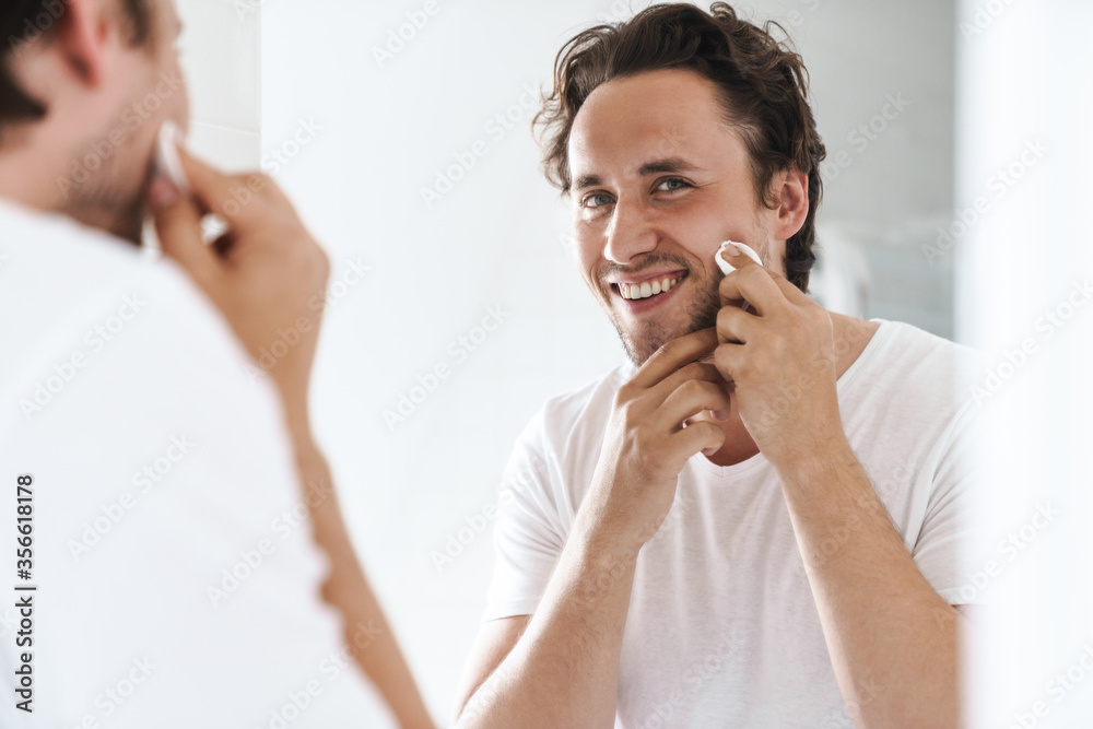 Attractive young man standing in front of the bathroom mirror
