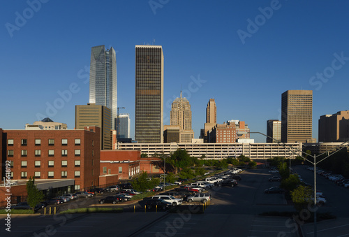 Looking across from Bricktown, towards downtown Oklahoma City with many tall buildings and bright early morning sunshine