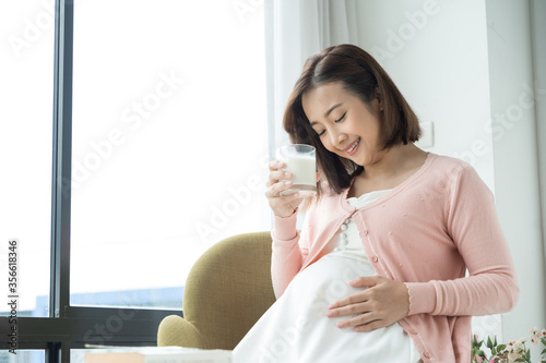 Young pregnant woman with glass of milk in the room
