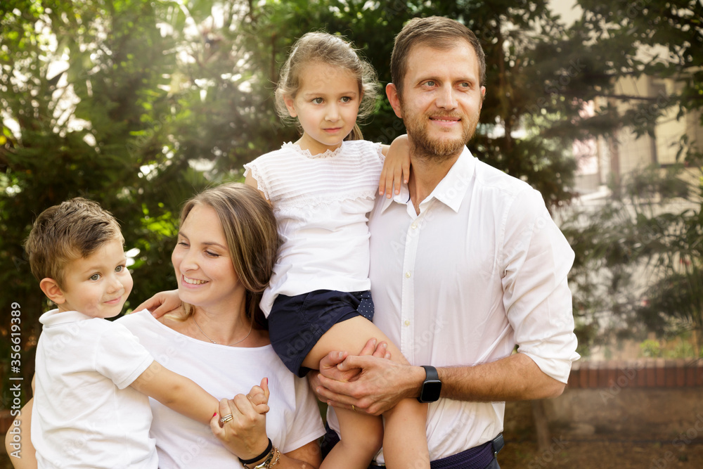 Bellissima famiglia composta da 2 genitori e figli si sraduna felice in gruppo nel giardino di casa Bellissima famiglia composta da 2 genitori e figli si sraduna felice in gruppo nel giardino di casa