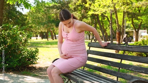 A pregnant woman sits on a bench due to severe pain