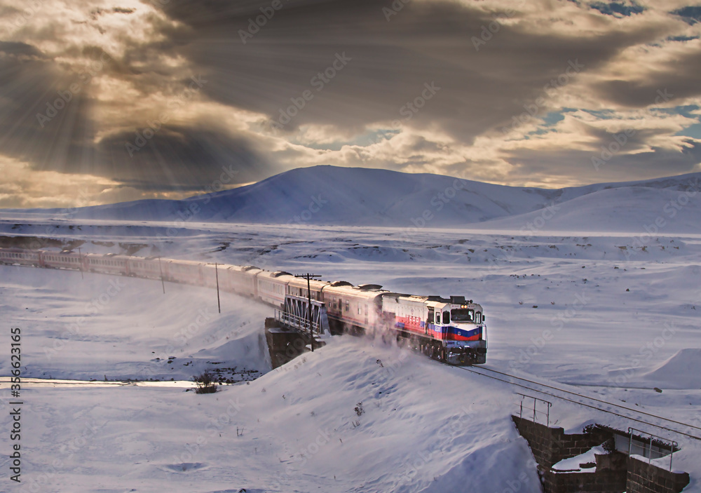 Kars, Turkey - January, 2018: Ankara-Kars (Diesel Train) Eastern Express train in the winter with sunrise. The travel of Eastern Express (Dogu Ekspresi) takes 24 hours between Ankara and Kars. Kars, Turkey - January, 2018: Ankara-Kars (Diesel Train) Eastern Express train in the winter with sunrise. The travel of Eastern Express (Dogu Ekspresi) takes 24 hours between Ankara and Kars.