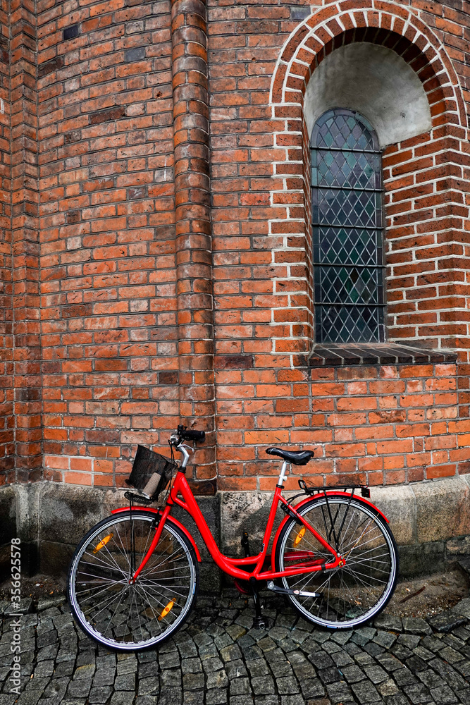 Aarhus, Denmark A red bicycle leaning up against the cathedral.