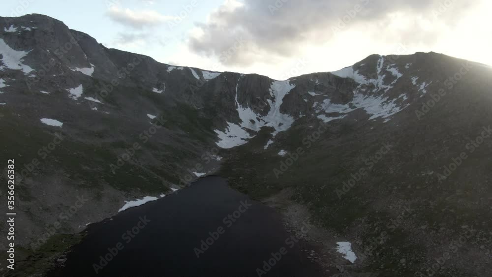 Aerial shot of lake by mountain with snow against sky, drone flying forward over natural landscape - Mount Evans, Colorado