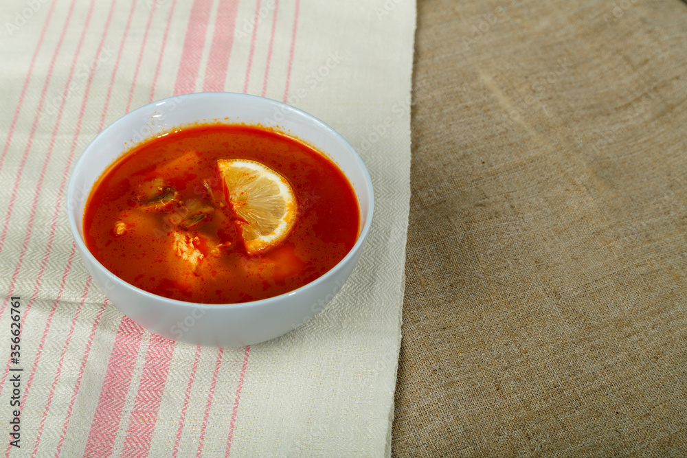 Traditional Tom Yum soup with chicken in a plate on a tablecloth on a linen napkin. Traditional Tom Yum soup with chicken in a plate on a tablecloth on a linen napkin.