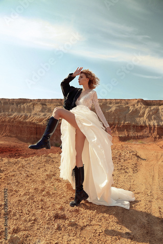 sensual woman with blond hair in elegant dress with accessories posing in the desert