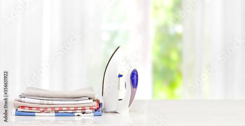  A stack of kitchen towels and an iron on a white table