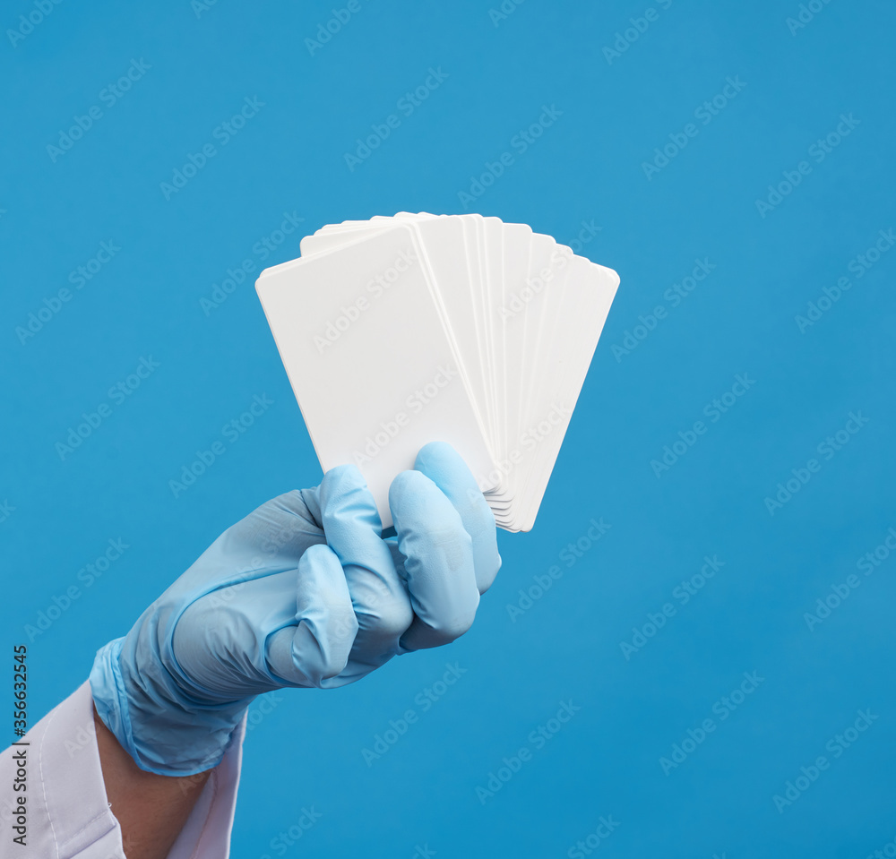 doctor hand in blue medical latex gloves holds an empty paper business card