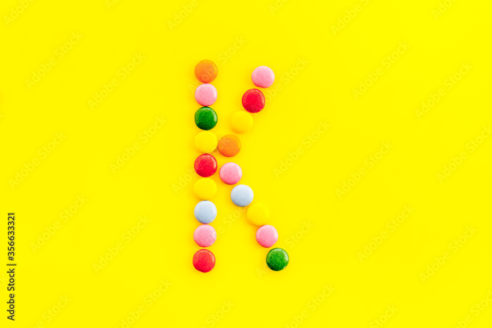 Letter K - alphabet made with sweets on yellow from above Letter K - alphabet made with sweets on yellow from above