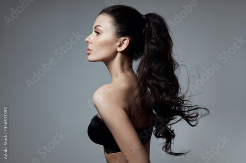 Sexy fashion woman with long hair, curly strong hair of a brunette girl in lingerie. Natural cosmetics for hair care, strong roots