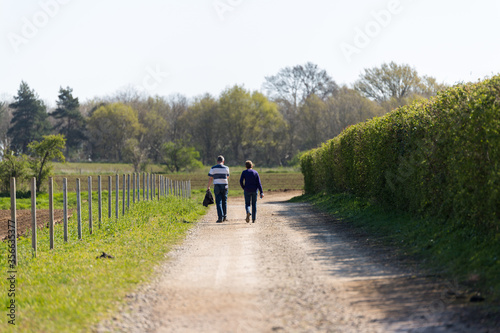 A middle aged couple taking a walk through the rural countryside on a bright and sunny day