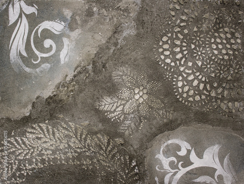 sample of factured plaster surface of the grey wall with floral ornament