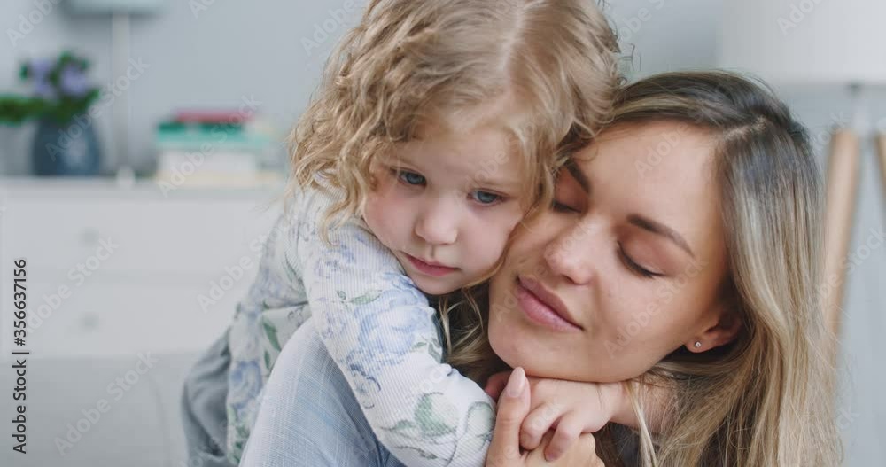 Close up portrait of happy little girl hugging mother enjoying loving mom embracing daughter at home. Happy mom having fun together with cute little child. Concept of family, parenthood, togetherness. Close up portrait of happy little girl hugging mother enjoying loving mom embracing daughter at home. Happy mom having fun together with cute little child. Concept of family, parenthood, togetherness.