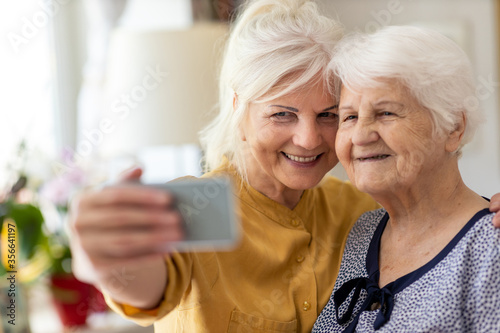 Senior woman and her adult daughter using smartphone together 