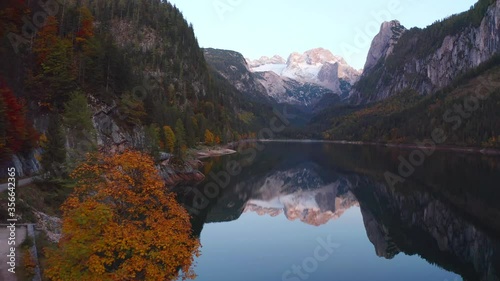 4k drone forward video (Ultra High Definition). Fantastic sunset on Gosausee (Vorderer) lake with Dachstein glacieron background. Evening autumn scene of Alps, Austria, Europe.  photo