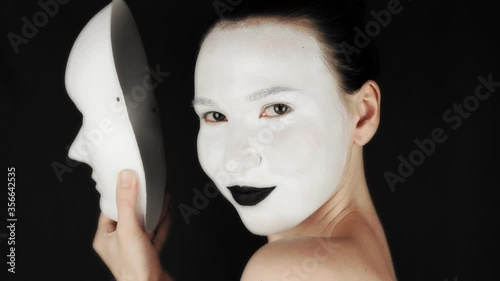 The girl takes off the theater mask and looks at the camera. The girl in theatrical makeup. Halloween concept. 4k footage