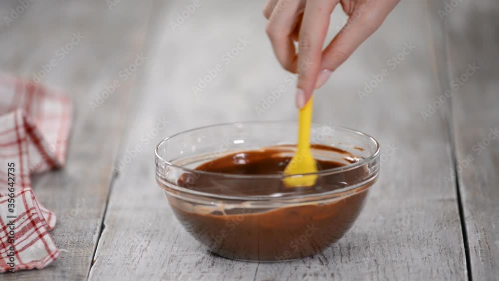 Woman with silicone spatula mixing a melted chocolate in bowl. Woman with silicone spatula mixing a melted chocolate in bowl.