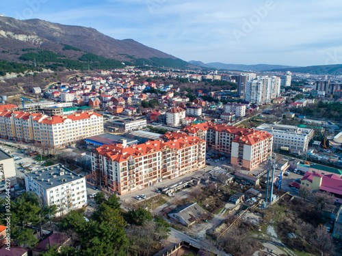 Two residential multi-storey apartment buildings with red roofs. A bird's-eye view. Located at the foot of the mountains on the shore of the sea Bay