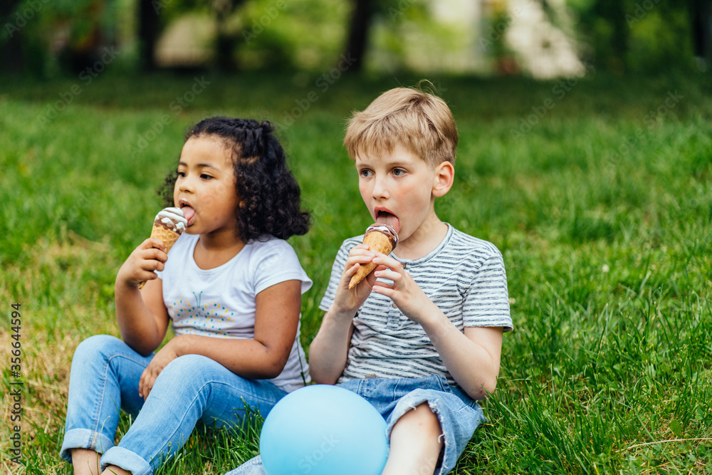 Cute little blond boy and mixed race hispanic little girl eating ice cream in close up. Different age multiethnic children enjoying time together. Cute little blond boy and mixed race hispanic little girl eating ice cream in close up. Different age multiethnic children enjoying time together.