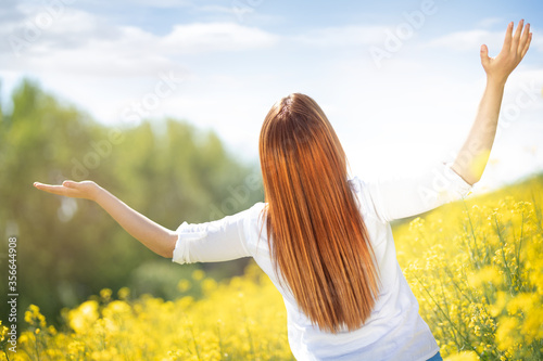woman with raised arms in yellow flowers