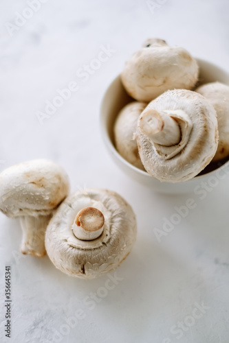 Champignon mushrooms in a white bowl on the table close-up.